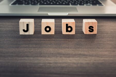 Technology Computer and Job Occupation Concept, Searching Information Data Creative Idea and Wooden Cube With Text in Front of Laptop.の写真素材