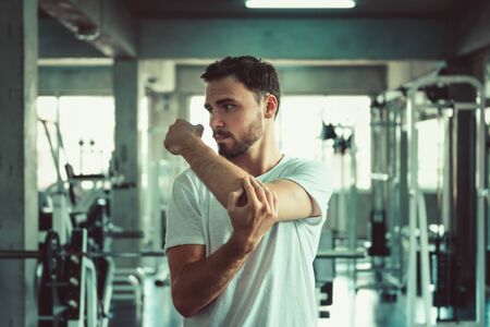 Handsome Man is Warm-Up Exercising Before Working Out in Fitness Club. Portrait of Strong Man Doing Workout Calories Burning in Gym. Healthy and Fitness Lifestyle Concept.の写真素材