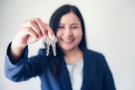 Business Woman in Uniform Suit Showing Keys for Rent Estate Housing , Beautiful of Businesswoman Broker Giving a Key to Customer, Business Property Real Estate Selling or Rental Concept.の写真素材