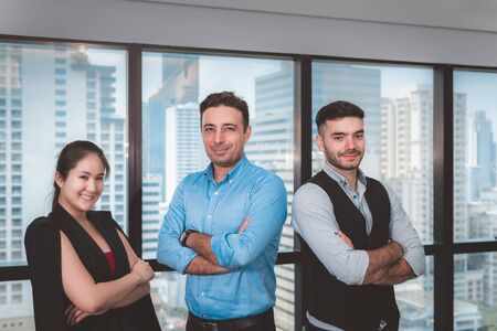 Business People Teams are Standing Beside Windows Frame in Office Workplace, Confident Business Working Teamwork in Arms Crossed Posing While Looking at Camera. Occupation and Financial Conceptの写真素材