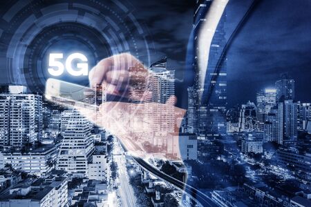 Business Technology Telecommunication and Communication 5G Network Connection Concept, Double Exposure of Businesswoman Using Mobile Phone With Graphic Media Screen and Cityscape Skyscrapers.の写真素材