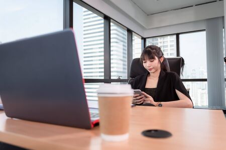 Business Woman Finance Accountant Using Mobile Phone for Chat Communicating While Working With Computer in Her Office Desktop, Business Financial Accounting and Technology Communication Concept.の写真素材