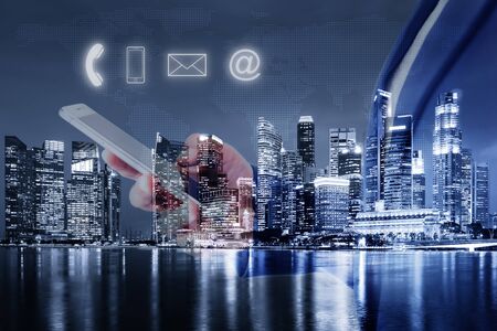Technology Communication Network and Contact Address Information Concept, Double Exposure of Business Woman is Using Mobile Phone to Communicating Against Skyscraper and Icon Multimedia Background.の写真素材