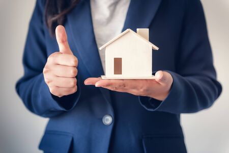Business Property Selling and Estate Investment Concept, Close-Up of Business Woman in Suit Showing House Model With Giving Thumbs Up Against Isolated White Background., Business Real Estate Investingの写真素材