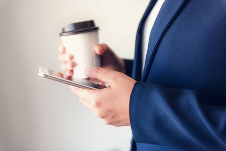 Business Technology Telecommunication and Communication Network Connection Concept, Close-Up of Businesswoman is Using Mobile Phone for Communicating Information While Holding a Cup of Coffeeの写真素材