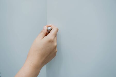 Close-Up of Woman Hand is Opening Door Cabinet in Kitchen Room, Female Hands is Pulling Wooden Door Cupboard in Pantry Room. Furniture Detailing and Household Conceptの写真素材