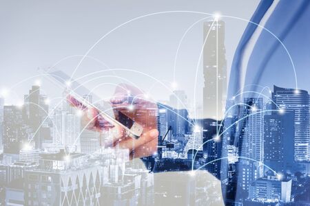 Business Technology Telecommunication and Communication 5G Network Connection Concept, Double Exposure of Businesswoman Using Mobile Phone With Graphic Media Screen and Cityscape Skyscrapers.の写真素材