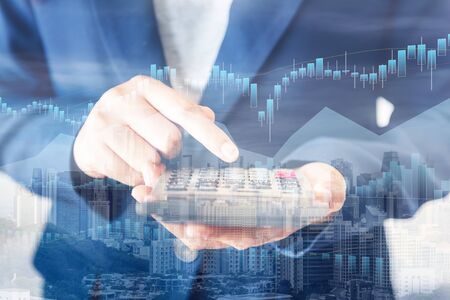 Business Accountant Woman Using Calculator for Calculating Financial Investment Tax Income and Profit Estimate, Double Exposure of Businesswoman Hands is Holding Calculator With Cityscape Backgroundの写真素材