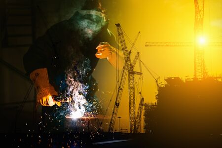 Double Exposure of Craftsman Welder is Welding Steel Frame on Construction Site Background, Welder Man in Safety Protective Equipment Doing Structure Metalwork in Fabrication Site. Engineering Skillsの写真素材