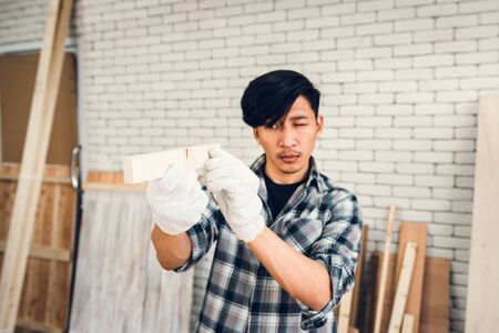 Carpenter Man is Working Timber Woodworking in Carpentry Shop, Craftsman is Aiming Alignment Timber Plank for Wooden Furniture in Workshop. Workmanship and Job Occupation Conceptの写真素材
