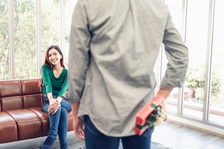 Romantic Surprise and Couple Love Valentine Concept, Young Man is Presenting Surprised to His Girlfriend at Home. Beautiful Woman Having Happiness and Surprise While Her Boyfriend Giving Presents Box.の写真素材