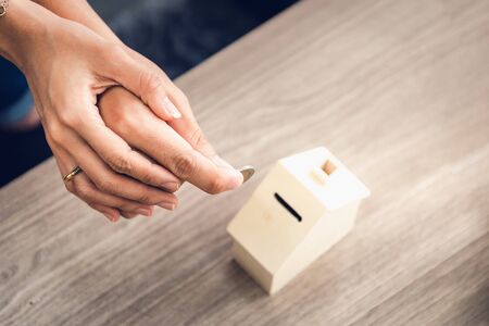 Couple Hands are Putting Money Coin into House Saving for Future Real Estate Together, Housing Insurance and Residential Loan Investment Concept.の写真素材