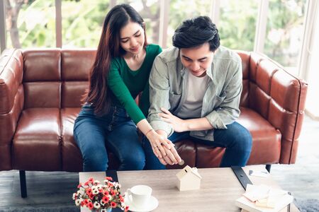 Portrait of Couple Love are Putting Money Coin into House Saving for Future Real Estate Together., Housing Insurance and Residential Loan Investment Concept.の写真素材