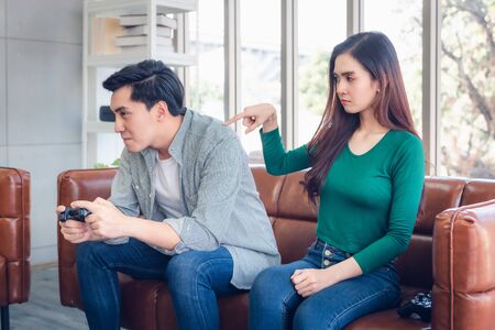 Portrait of Woman Feeling Offended With Her Boyfriend When He Playing Video Games While Sitting on The Couch in Living Room. Couple Love Relationship and Lifestyles Concept.の写真素材
