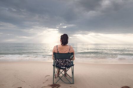 Freelancer Woman is Working on Tablet While Travel Vacation Trip at The Beach, Smart Woman is Using Tablet for Communication and Entertainment at Outdoor Sand Beach. Freelance and Relaxation Concept.の写真素材