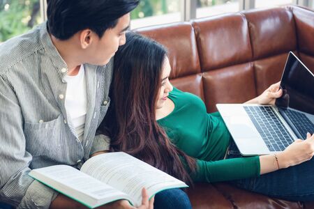 Couple Love Having Enjoy Relaxation on Sofa at Their Home, Attractive Asian Couple Happiness in Romantic Moments at Living Room While Reading Magazine and Work at Home. Relaxing and Lifestyles Conceptの写真素材
