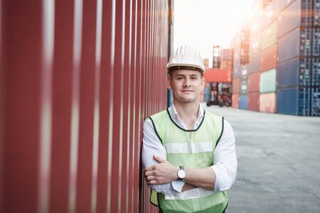 Portrait, Confident Transport Engineer Man in Safety Equipment Standing in Container Ship Yard. Transportation Engineering Management and Container Logistics Industry, Jobs Shipping Occupationの写真素材