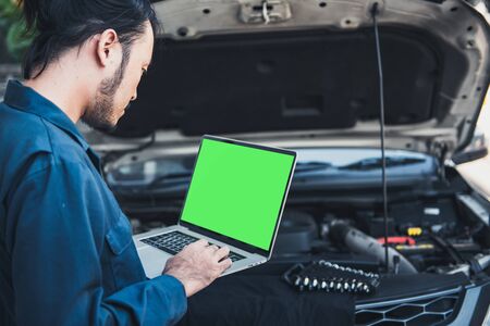 Mechanic Engineer is Diagnosing Car Engine and Electric Adjusting Transmission With Computer Laptop, Automobile Service Man Diagnostic Vehicle Car Engines Systems in Garage Workshop. Engineering Workの写真素材