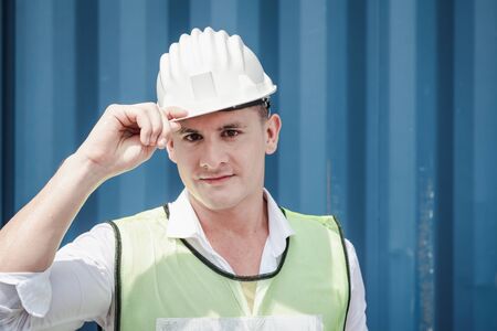 Portrait Confident Transport Engineer Man in Safety Equipment Standing in Container Ship Yard. Transportation Engineering Management and Container Logistics Industry, Jobs Shipping Worker Occupationの写真素材