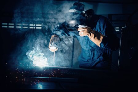 Technical Welder is Working Steel Welding in Assembly Workshop, Welder Structure in Safety Equipment is Welding Metal in Factory Assembling Production Line. Labor Skill and Construction Occupationの写真素材