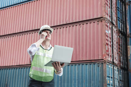 Container Logistics Shipping Management of Transportation Industry, Transport Engineer Managing Control Via Computer Laptop in Containers Shipyard. Business Cargo Ship Import/Export Factory Logistic.の写真素材