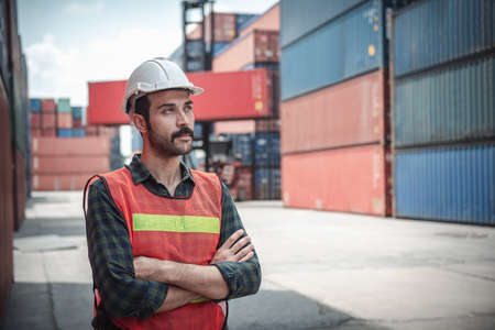 Portrait of Confident Transport Engineer Man in Safety Equipment Standing in Container Ship Yard....