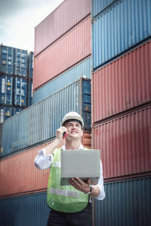Container Logistics Shipping Management of Transportation Industry, Transport Engineer Managing Control Via Computer Laptop in Containers Shipyard. Business Cargo Ship Import/Export Factory Logistic.の写真素材