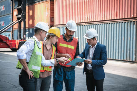 Transport Container Shipping Worker Team Meeting Discussion About Freight Control at Cargo Import/Export Logistic Warehouse. Transport Engineers Teamwork Brainstorming Their Containers Ship Project.の写真素材