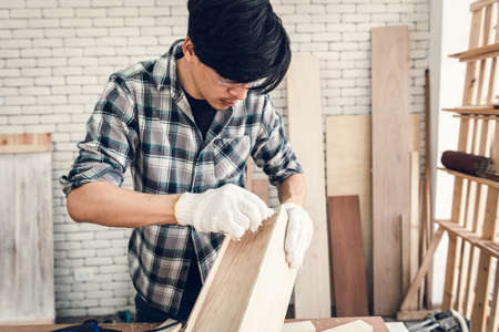 Carpenter Man is Working Timber Woodworking in Carpentry Workshops, Craftsman is Applying Glue to Timber Plank for Wooden Furniture in Workshop. DIY Workmanship, Job Carpenters Conceptの写真素材