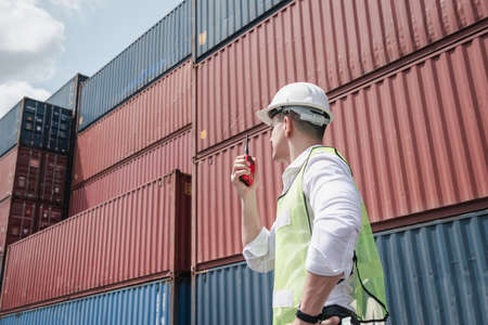 Container Logistics Shipping Management of Transportation Industry, Transport Engineer Managing Control Via Walkie Talkie in Containers Shipyard. Business Cargo Ship Import/Export Factory Logistic.の写真素材