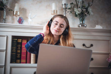 Leisure Activity and Home Relaxing Lifestyle Concept, Attractive Woman Having Enjoyment While Listening Music Songs Via Headphone on Laptop in Living Room. Relaxation Pursuit Entertainment at Homeの写真素材