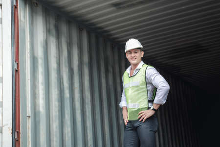 Container Logistics Shipping Management of Transportation Industry, Portrait of Transport Engineer Man Working Control Containers in Ship Yard. Business Cargo Ship Import/Export Factory Logistic.の写真素材