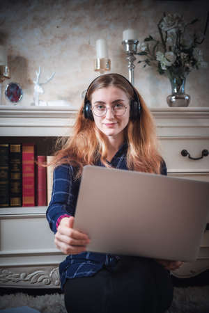 Leisure Activity and Home Relaxing Lifestyle Concept, Attractive Woman Having Enjoyment While Listening Music Songs Via Headphone on Laptop in Living Room. Relaxation Pursuit Entertainment at Homeの写真素材