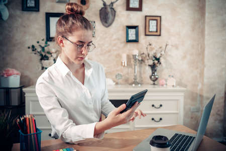 Business Entrepreneur Woman is Working on The Desk While Using Calculator for Calculating Marketing Financial in Home Office, Businesswoman Worker Busy Work at Home During Covid-19 Pandemic.の写真素材