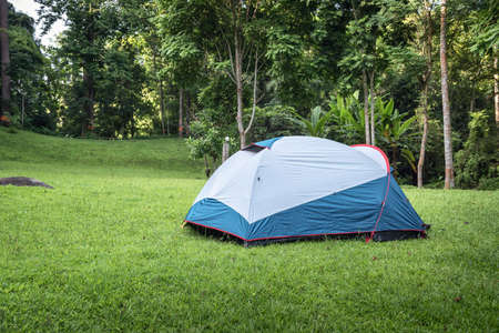Camping Campsite and Tent on Green Grass Under The Trees Tropical Forest, Field Campground for Vacation Outdoors Leisure Activity and Adventure. Backpack Trekking Tourist Lifestyles, Travel Adventuresの写真素材