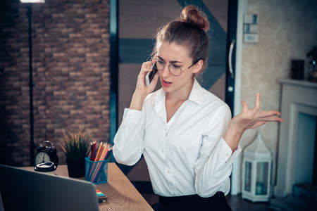 Business Entrepreneur Woman is Working on Table Desk While Calling on Mobile Phone for Own Business in Her Home Office, Businesswoman Worker Busy Work at Home During Covid-19 Pandemic.の写真素材
