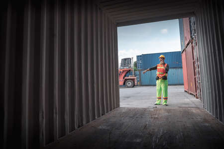 Container Supervisor Control Import/Export While Inspecting Containers Box in Warehouse Storage Distribution. Container Logistics Shipping Controlling of Transportation Industry, Cargo Ship Factoryの写真素材