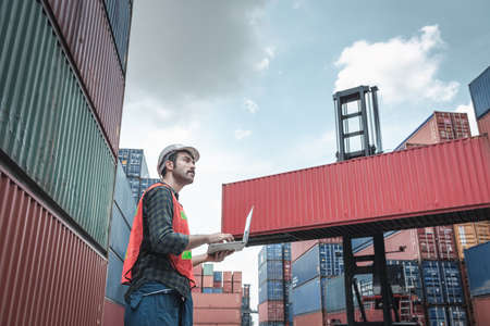 Container Supervisor Control Import/Export While Inspecting Containers Box in Warehouse Storage Distribution. Container Logistics Shipping Controlling of Transportation Industry, Cargo Ship Factoryの写真素材