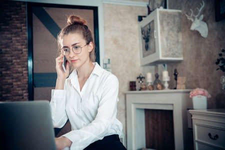 Business Entrepreneur Woman is Working on Table Desk While Calling on Mobile Phone for Own Business in Her Home Office, Businesswoman Worker Busy Work at Home During Covid-19 Pandemic.の写真素材