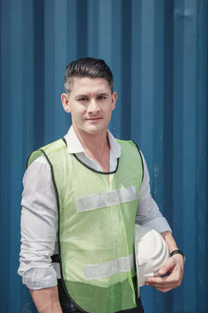 Portrait of Containers Ship Engineer Control Import/Export Standing Against Box Container Background. Container Logistics Shipping Controlling of Transportation Industry, Transport Cargo Shipの写真素材