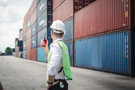Container Supervisor Control Import/Export While Inspecting Containers Box in Warehouse Storage Distribution. Container Logistics Shipping Controlling of Transportation Industry, Cargo Ship Factoryの写真素材