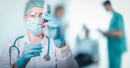 Lab Scientist or Female Doctor Medicine Science is Injecting Blood Syringe into Sample Tube for Experiment Biology in Clinic Laboratory. Doctors Team Diagnosing Patient Health in Examination Roomの写真素材