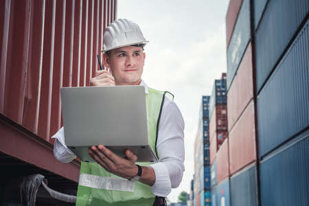 Container Logistics Shipping Management of Transportation Industry, Transport Engineer Managing Control Via Computer Laptop in Containers Shipyard. Business Cargo Ship Import/Export Factory Logistic.の写真素材