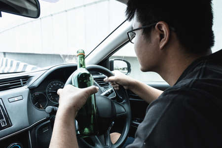 Man Driver Drinking Alcohol and Drunk While Driving a Car, Drunken Man Lose Control and Visual Visibility During Drive a Vehicle Car. Illegal Violation and Accident Risk.の写真素材