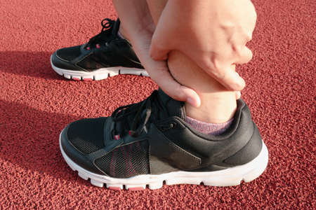 Female Athlete Runner Ankle Injury While Jogging in Running Track, Sport Woman Having Pain Her...