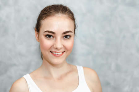 Portrait of Young Beautiful Cheerful Girl Looking at Camera Against Gray Background. Close-Up Portrait of Happy Cheerful Young Woman With Beauty Smiling Expression on Isolated Backgrounds.の写真素材