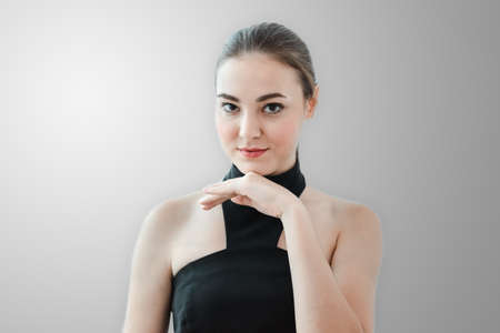 Portrait of Young Beautiful Cheerful Girl Looking at Camera Against Gray Background. Close-Up...