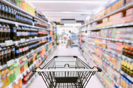 Abstract Defocused Blurred of Consumer Goods and Shopping Cart in Supermarket Store, Shop Trolley Basket in Department Store. Business Retail Customer Shopping Mall Service, Convenience Supermarketsの写真素材