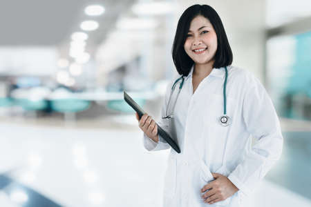 Healthcare and Medical Consulting Concept, Female Medicine Doctor With Holding Stethoscope Standing Against Examination Room Background. Business Health Consultation Hospital and Checkup Diseaseの写真素材