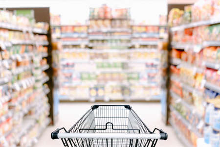 Abstract Defocused Blurred of Consumer Goods and Shopping Cart in Supermarket Store, Shop Trolley Basket in Department Store. Business Retail Customer Shopping Mall Service, Convenience Supermarketsの写真素材